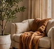 Cozy armchair with a warm brown throw and a leafy plant