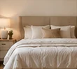 Restful neutral bedroom with ivory bedding and a taupe headboard